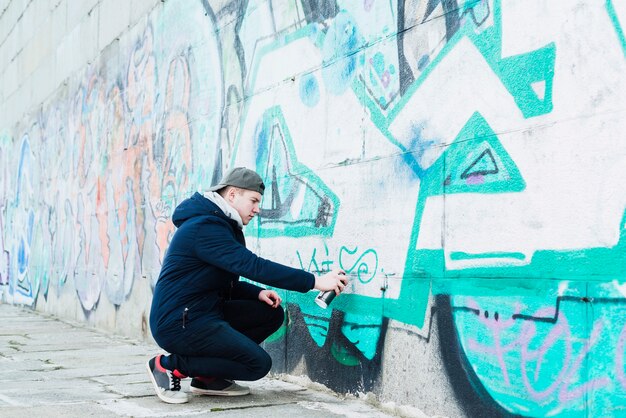 Hombre dibujando en la pared con pintura en aerosol