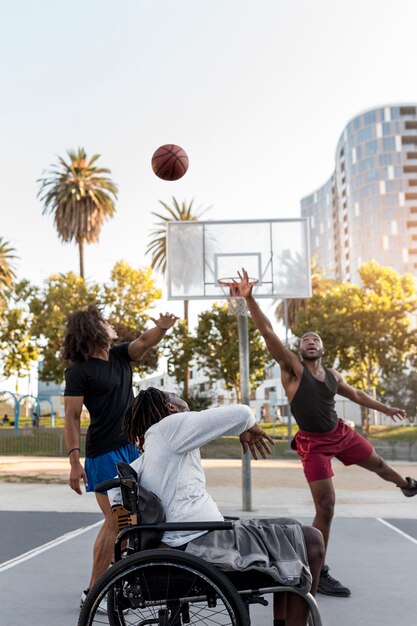 Hombre discapacitado en silla de ruedas jugando baloncesto con personas