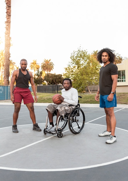 Hombre discapacitado en silla de ruedas jugando baloncesto con sus amigos