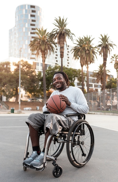 Foto gratuita hombre discapacitado en silla de ruedas con una pelota de baloncesto