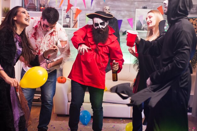 Hombre disfrazado de pirata bailando alrededor de sus amigos celebrando halloween.