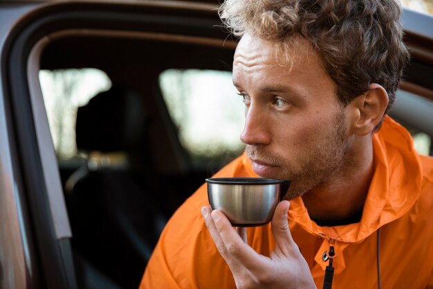 Hombre disfrutando de una bebida caliente en la taza durante un viaje por carretera