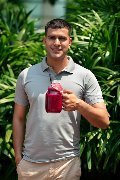 Foto gratuita hombre disfrutando de una bebida de fruta del dragón al aire libre