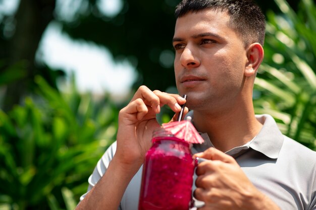 Hombre disfrutando de una bebida de fruta del dragón al aire libre