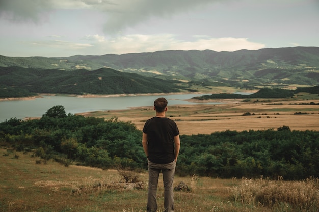 Un hombre disfrutando de la hermosa vista tomada desde atrás