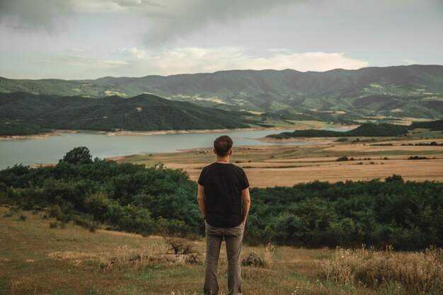 Un hombre disfrutando de la hermosa vista tomada desde atrás