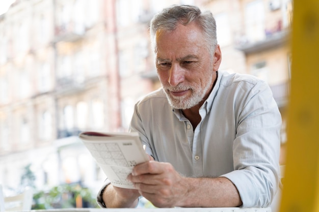 Foto gratuita hombre disfrutando de un juego de sudoku en papel por sí mismo