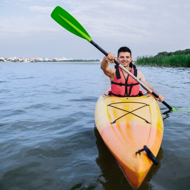 Hombre disfrutando el kayak en el lago idílico