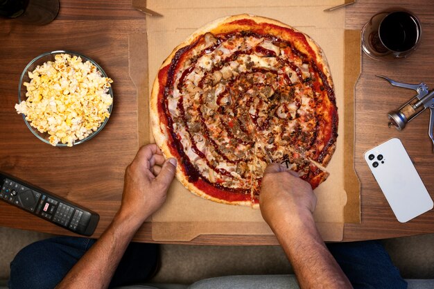 Hombre disfrutando de una pizza mientras está solo en casa