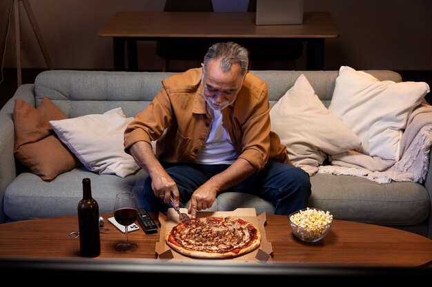 Hombre disfrutando de una pizza mientras está solo en casa