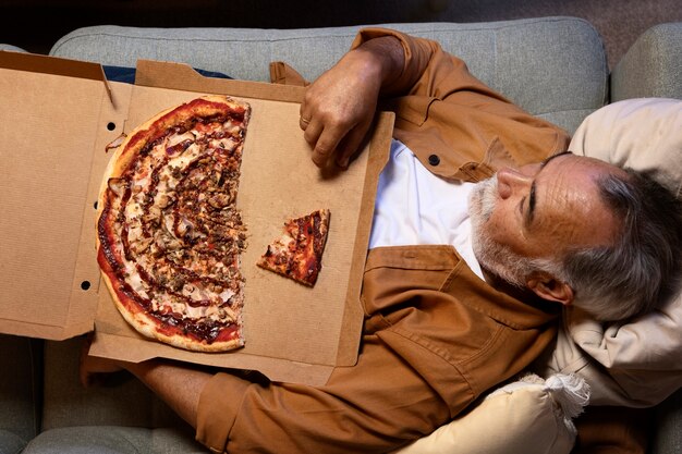 Hombre disfrutando de una pizza mientras está solo en casa