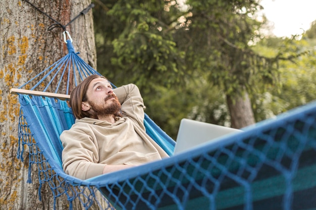 Hombre disfrutando de su tiempo en la naturaleza mientras está sentado en la hamaca