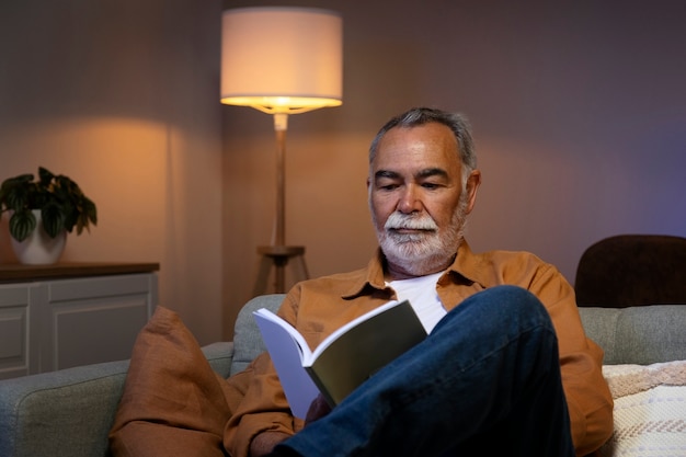 Foto gratuita hombre disfrutando de su tiempo a solas en casa mientras lee un libro