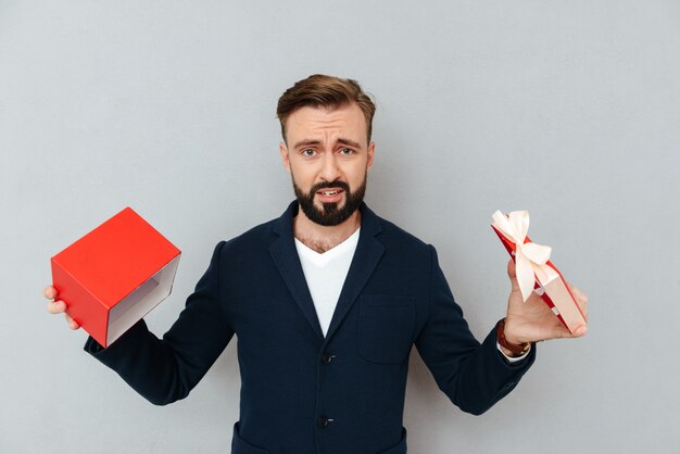 Hombre disgustado mirando la cámara y sosteniendo regalo vacío aislado