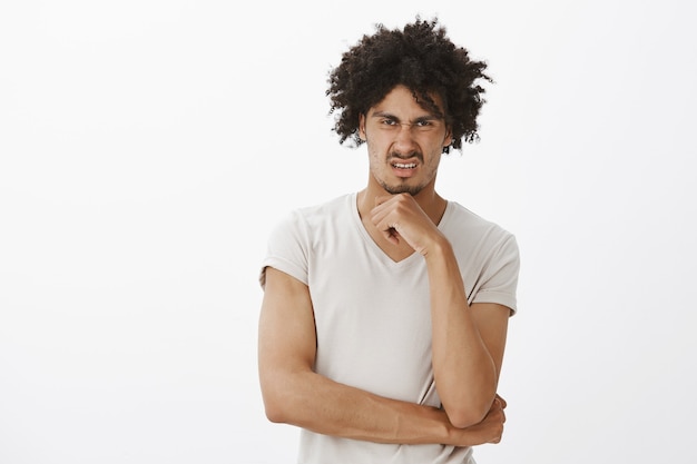 Hombre divertido disgustado haciendo muecas, encogiéndose de algo horrible