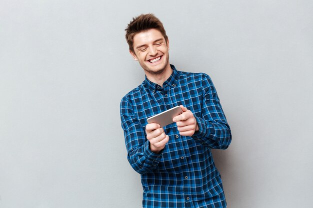 Hombre divertido riendo mientras juega con el teléfono inteligente