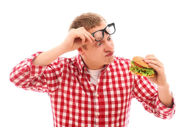 Hombre divertido en vasos comiendo hamburguesas aislado en un blanco