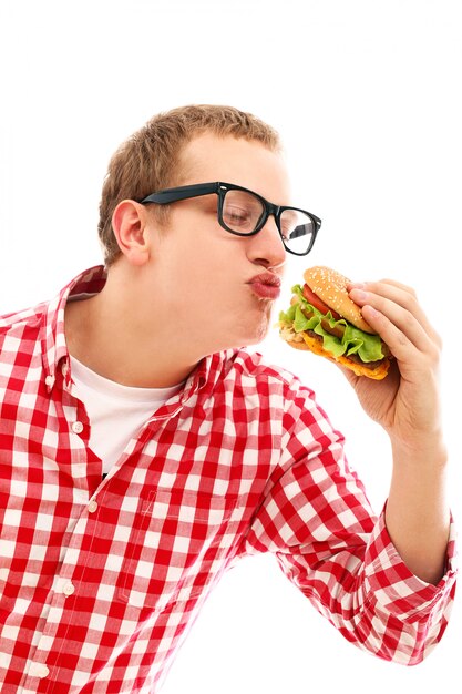 Hombre divertido en vasos comiendo hamburguesas aislado en un blanco