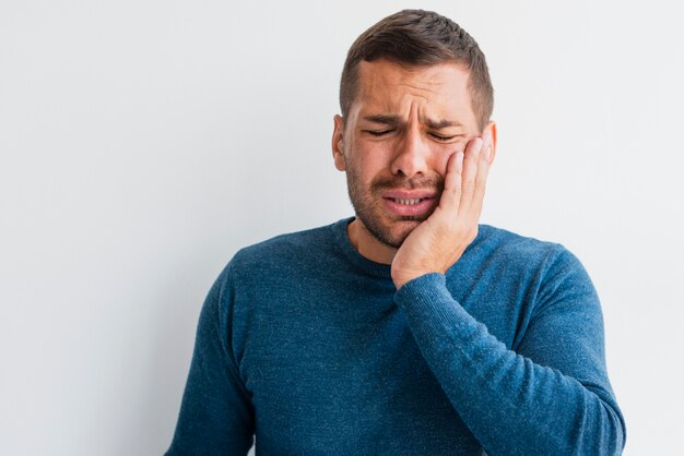 Hombre con dolor sosteniendo una mano en la cara