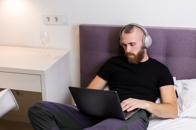 Foto gratuita hombre en el dormitorio en la cama se quedó dormido frente a la computadora portátil