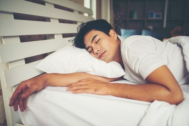 Hombre durmiendo en la cama por la mañana