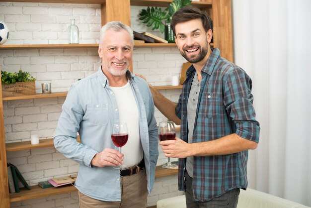 Hombre de edad y chico sonriente joven con copas de vino