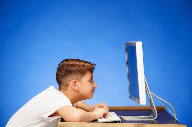 Foto gratuita hombre en edad escolar sentado frente al monitor portátil