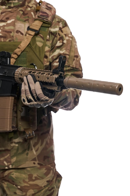Hombre del ejército anónimo con guantes tácticos sosteniendo un rifle de asalto en el pecho interior vista de cerca del cañón