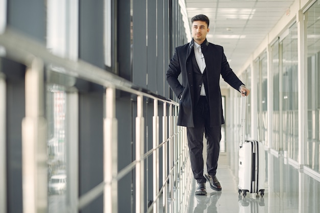 Hombre elegante en el aeropuerto con una maleta