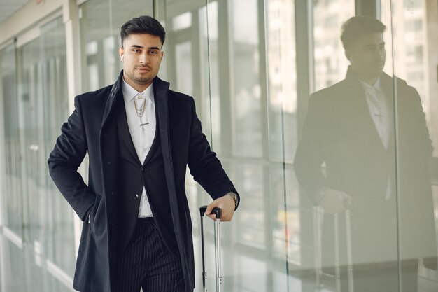 Hombre elegante en el aeropuerto con una maleta