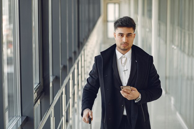 Hombre elegante en el aeropuerto con una maleta