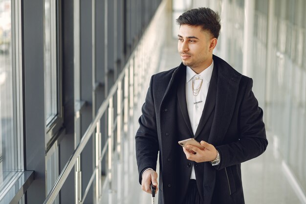 Hombre elegante en el aeropuerto con una maleta