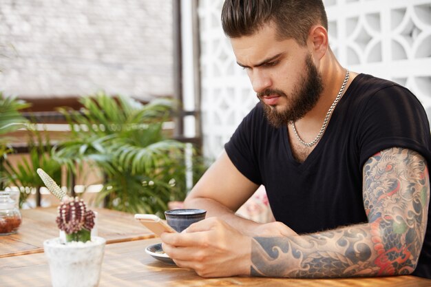 Hombre elegante barbudo sentado en la cafetería