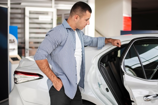 Hombre elegante comprobando un coche en concesionario