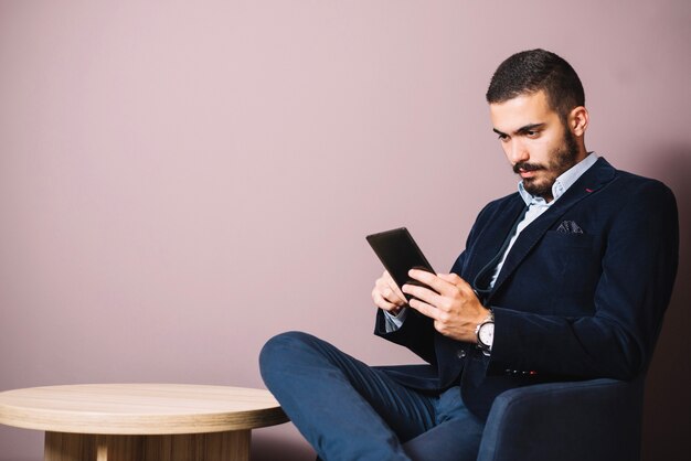 Hombre elegante concentrado con tableta