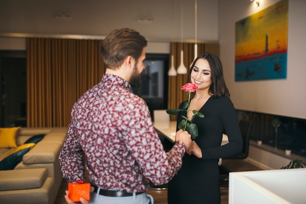 Hombre elegante dando rosa a mujer