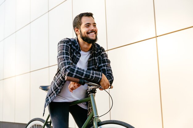 Hombre elegante divertido sentado en bicicleta, disfrutando del ocio al aire libre.