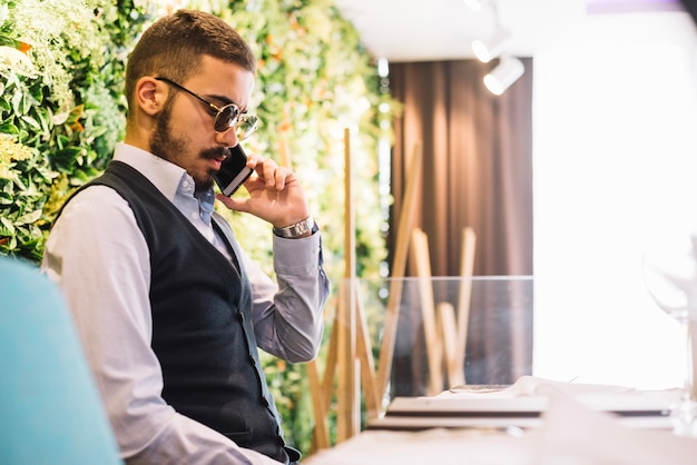 Hombre elegante hablando en teléfono inteligente en el café