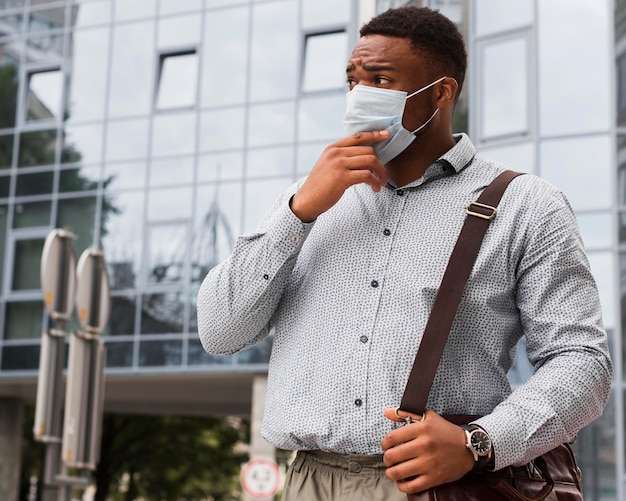 Hombre elegante con máscara en la cara camino al trabajo durante la pandemia