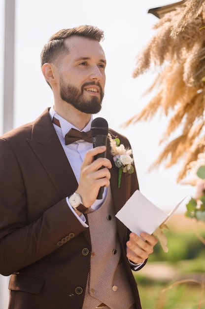 Hombre elegante con micrófono hablando el día de la boda