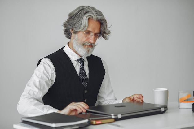 Hombre elegante en la oficina. Hombre de negocios con camisa blanca. El hombre trabaja con un portátil.