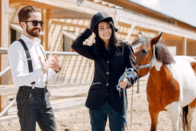 Hombre elegante de pie junto al caballo en un rancho con niña