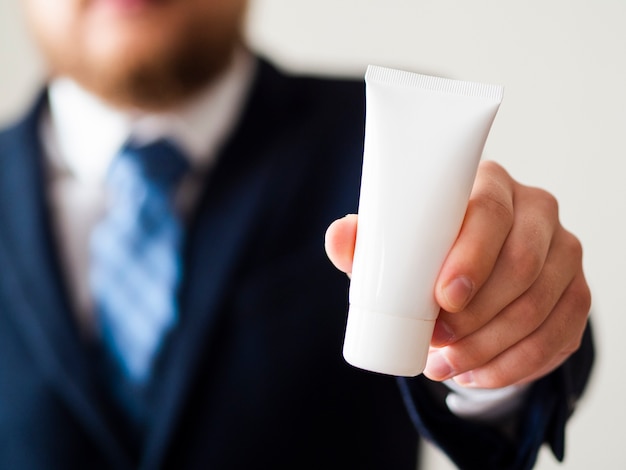 Foto gratuita hombre elegante primer plano sosteniendo la botella de crema