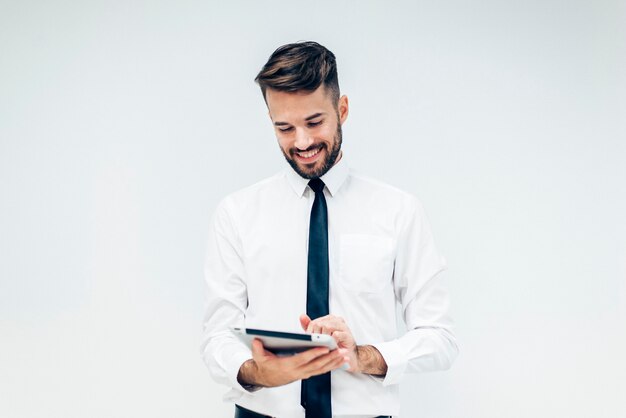 Hombre elegante sonriendo mientras mira una tableta