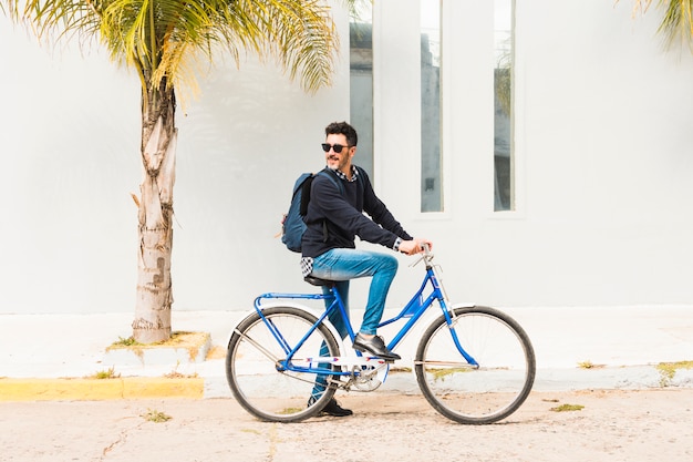 Hombre elegante con su mochila montada en bicicleta azul