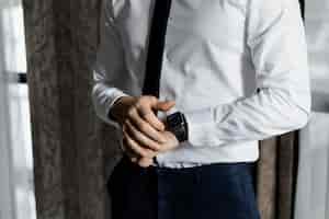 Foto gratuita hombre elegante vestido con una camisa blanca y corbata con un reloj inteligente