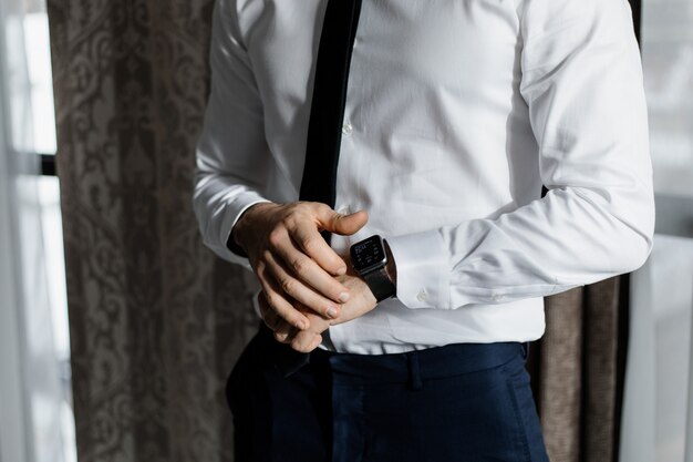 Hombre elegante vestido con una camisa blanca y corbata con un reloj inteligente