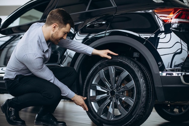 Hombre eligiendo un auto y revisando llantas