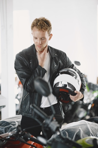 Foto gratuita el hombre eligió motocicletas en la tienda de motos. chico con chaqueta negra.