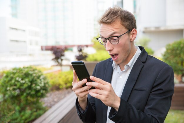 Hombre emocionado con celular recibiendo noticias impactantes